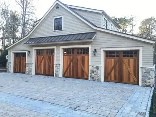 Detached garage with four wooden doors and a stone-accented exterior on a paved driveway