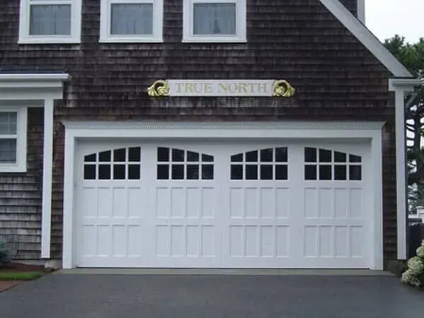 White double garage door on a gray house with a “True North” sign above it.
