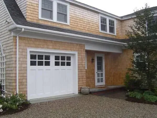 Suburban house exterior with beige siding, white garage door, and front entryway