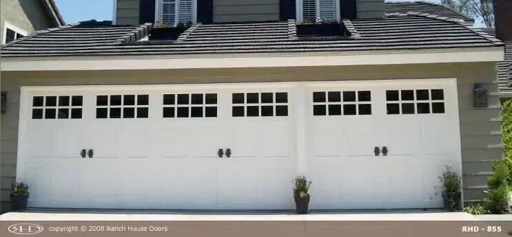 White three-car garage with black trim and a house facade above it