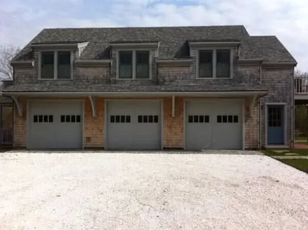 Large two-story house with three garage doors and a wide driveway