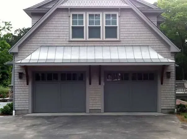 Gray two-car garage attached to a house with a metal roof and dormer windows