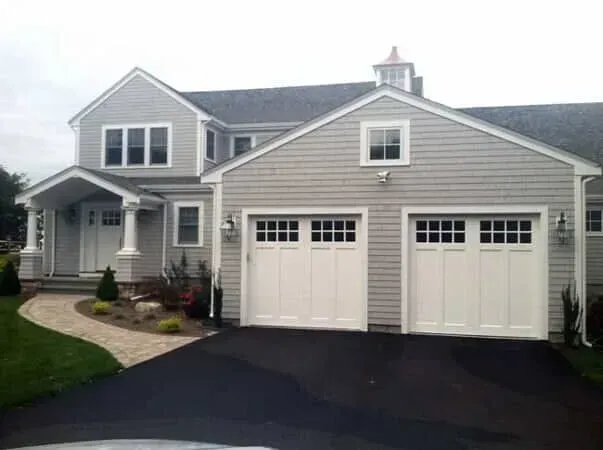Suburban house with gray siding, white trim, and two-car garage on a curved driveway