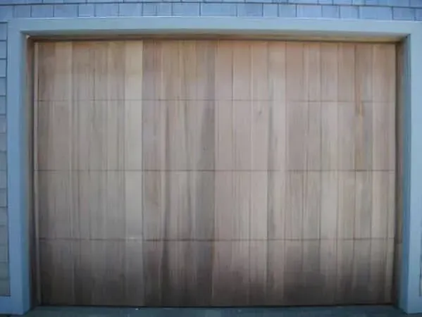 Closed wooden garage door framed by light blue siding and trim