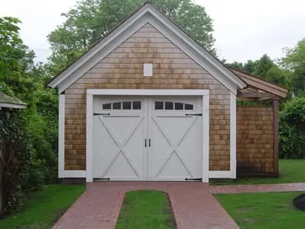 White double garage with gabled roof and small side extension beside a red brick walkway.