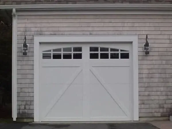 White garage door with small windows on a gray shingled house exterior