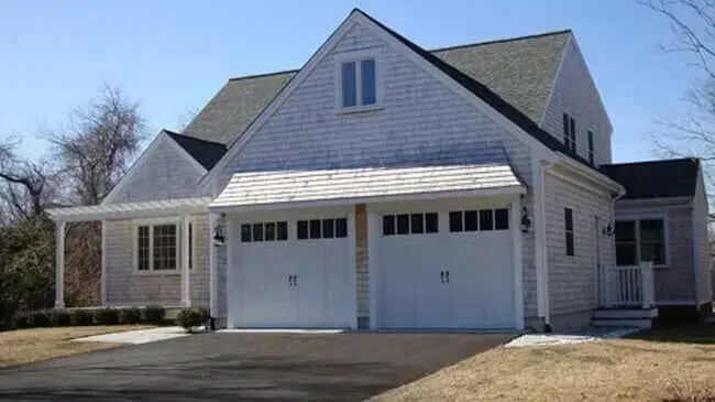 Suburban two-story house with white siding, attached double garage, and driveway in front