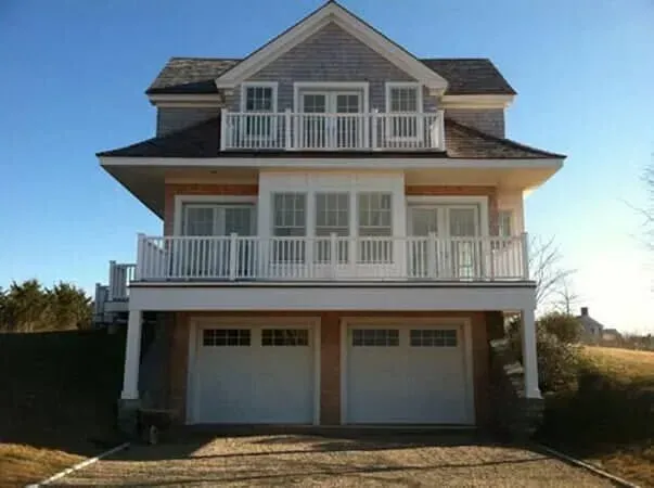 Large white house with balconies and two garage doors under a blue sky