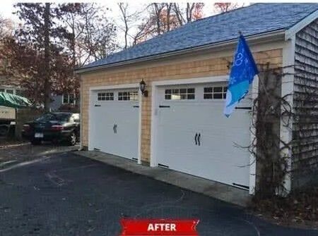Two white garage doors on a house driveway, with a blue flag hanging on the right side.