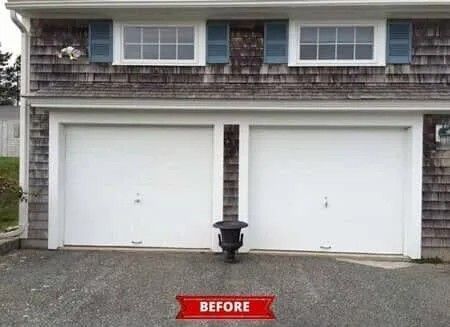 Two white garage doors on a house exterior with a small black planter between them