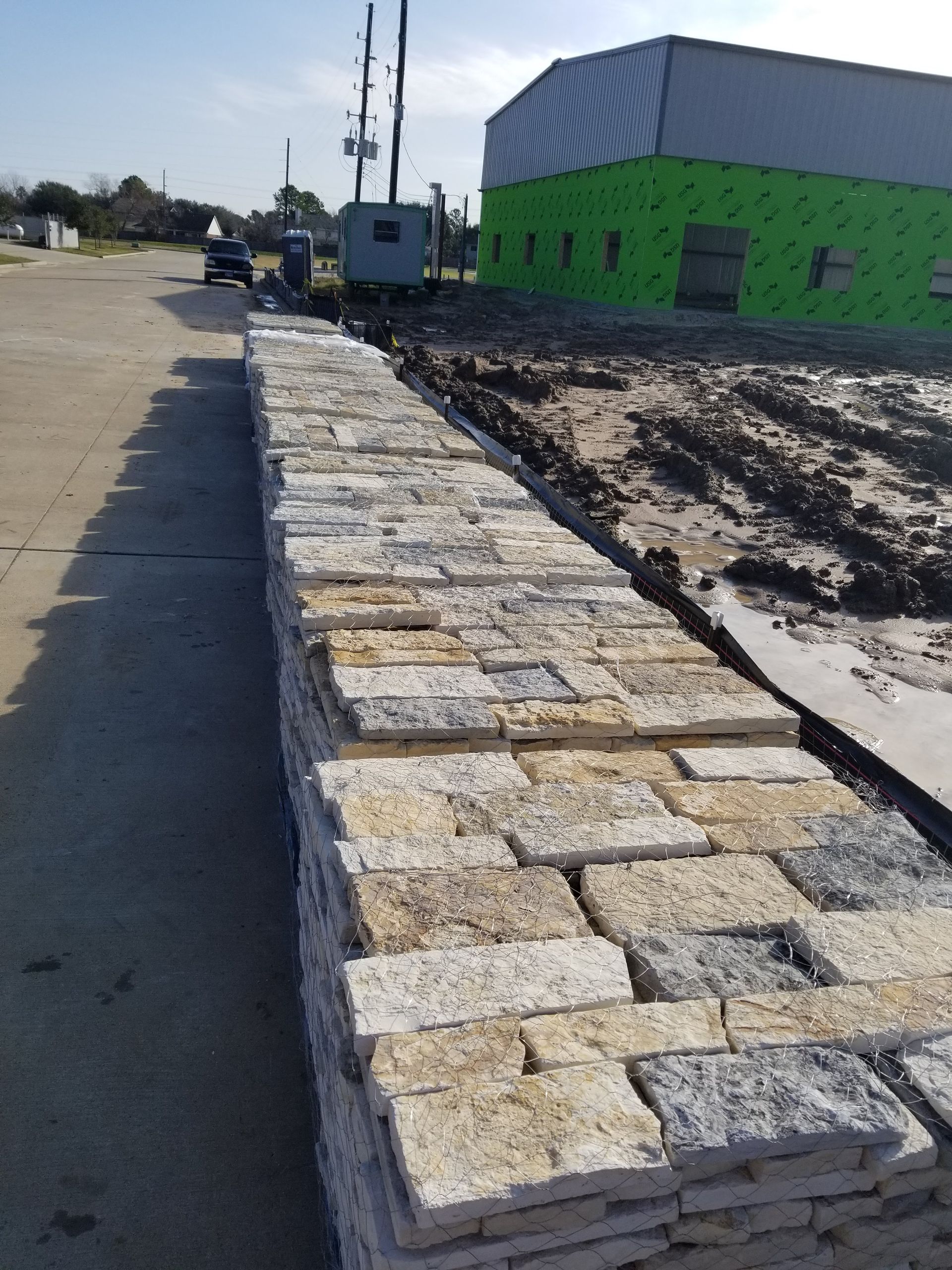 A row of bricks sitting on the side of a road in front of a building under construction.
