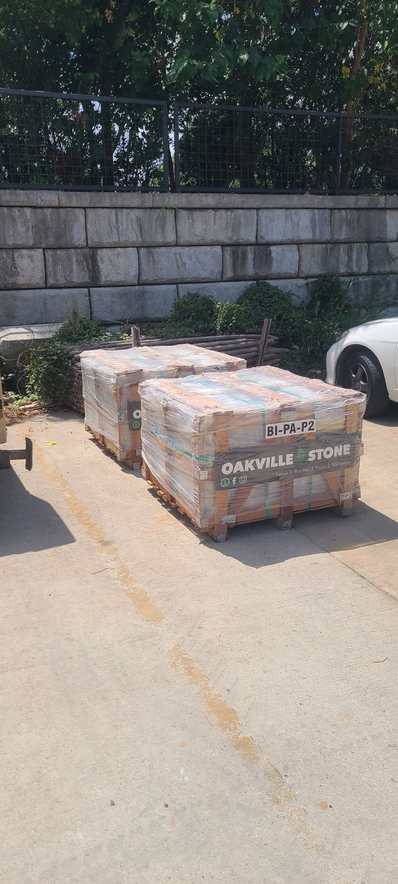 A bunch of pallets of bricks are sitting on the ground in a parking lot.