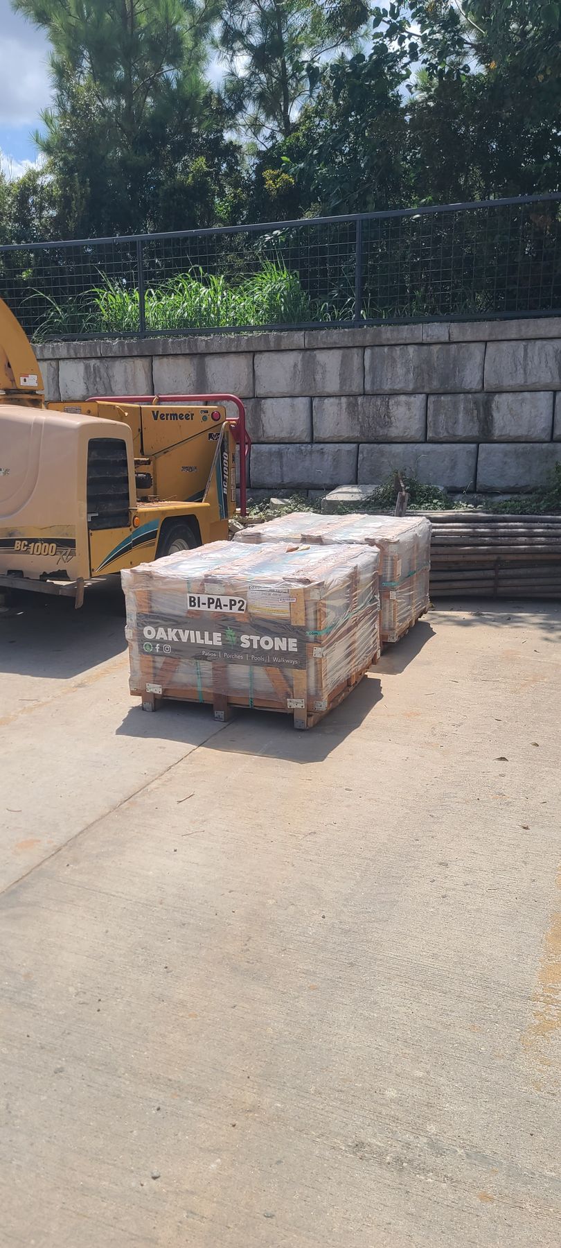 A pallet of bricks is sitting in a parking lot next to a yellow truck.