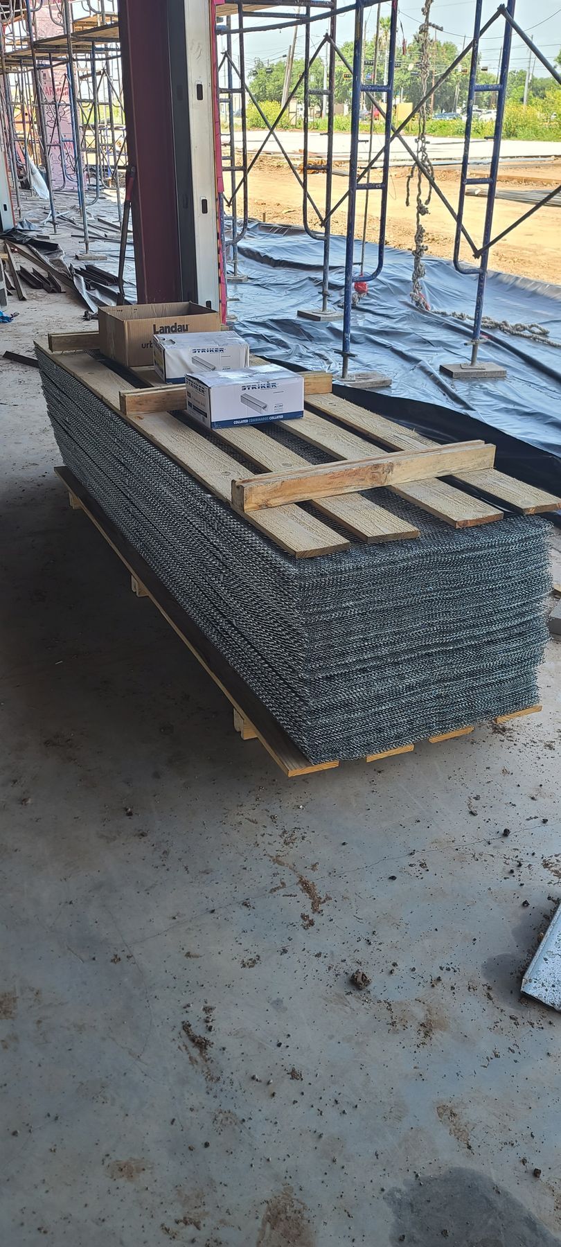 A pallet of scaffolding is sitting on the ground in a building under construction.