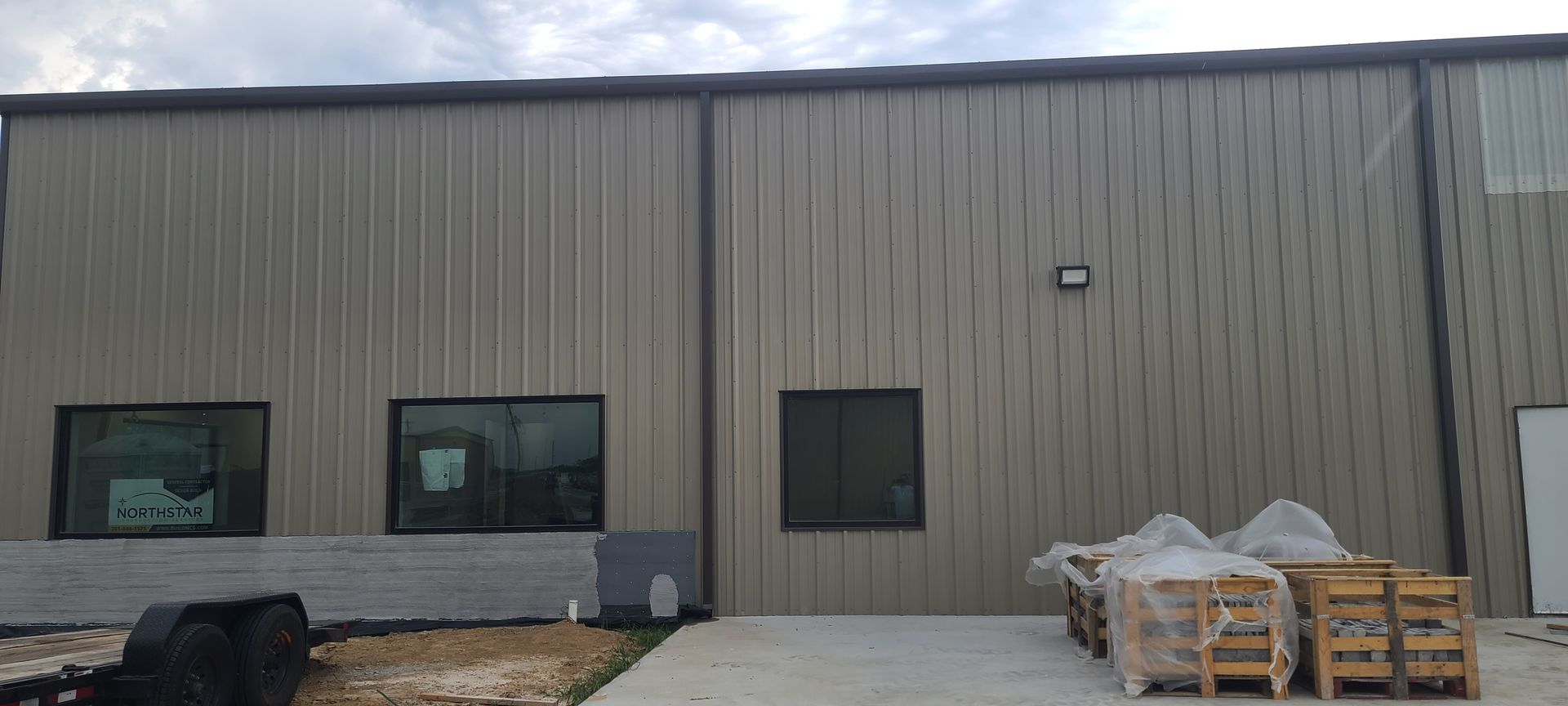 A large metal building with a lot of windows and a trailer parked in front of it.