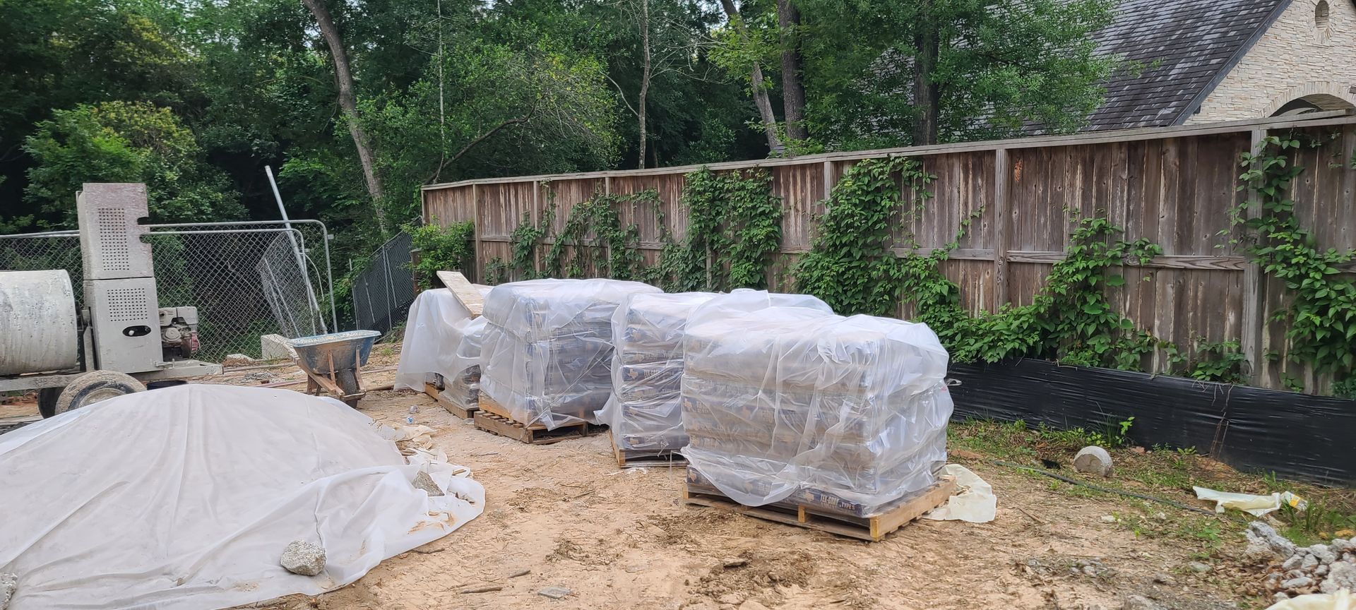 A bunch of bricks wrapped in plastic are sitting on top of a pile of dirt.