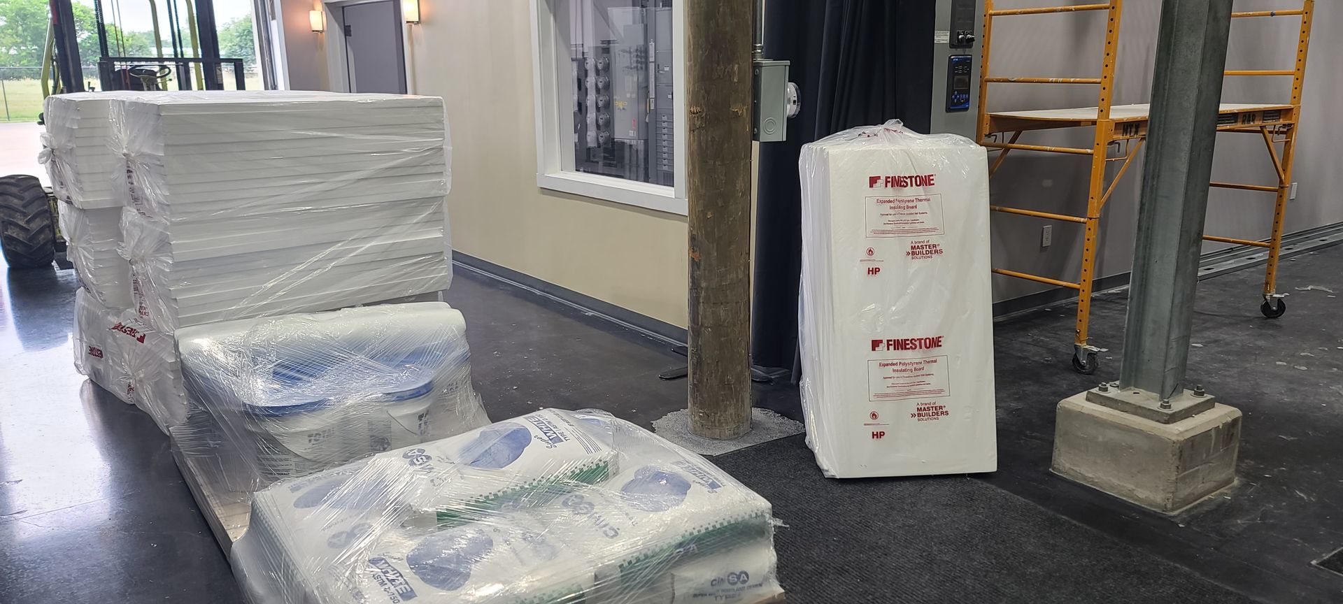 A stack of styrofoam blocks in a room with a scaffolding in the background.