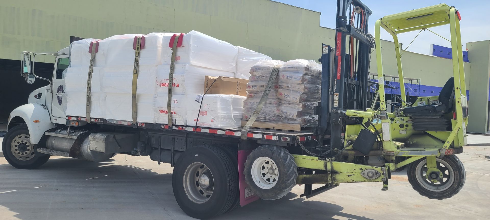 A truck with a forklift attached to it is parked in front of a building.