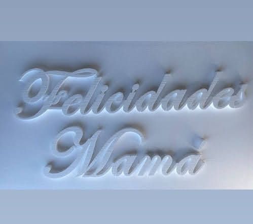 The word felicidades mama is written in Spanish on a white surface.