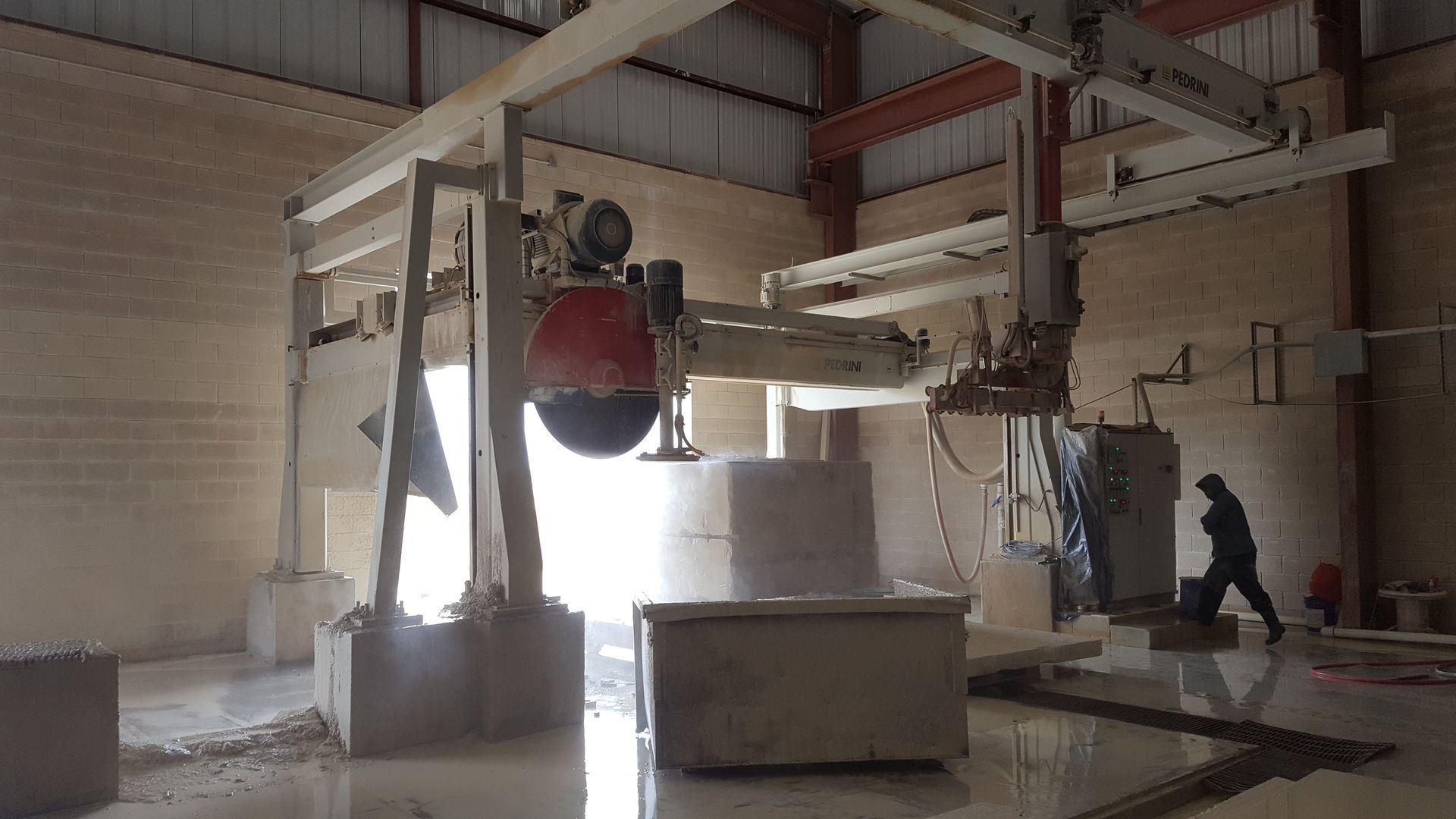 A man is standing in front of a machine in a warehouse.