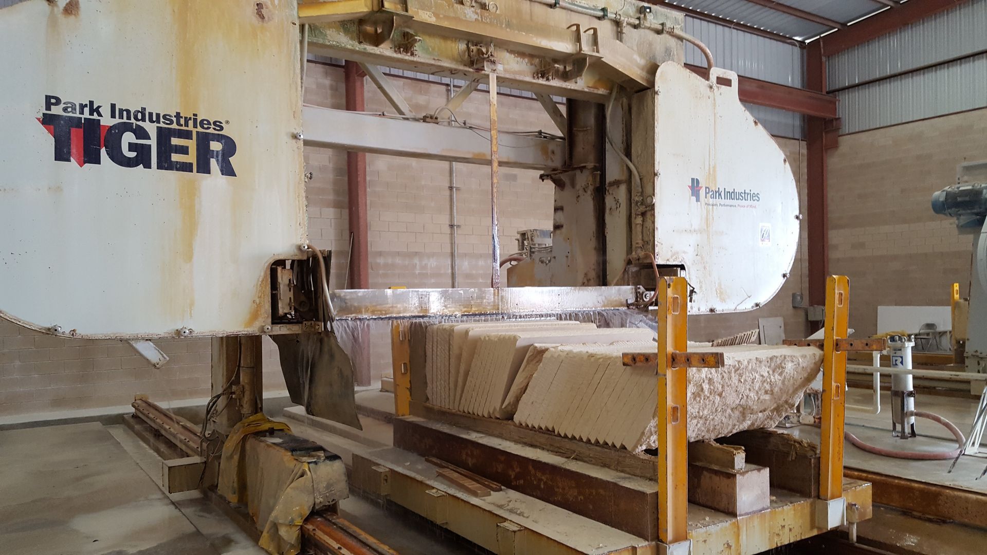 A large tiger machine is cutting a piece of wood in a factory.