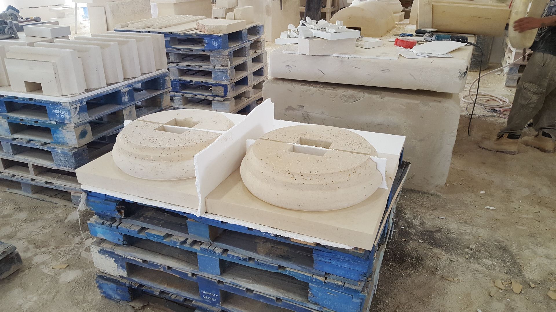 A man is standing next to a pile of concrete pallets.