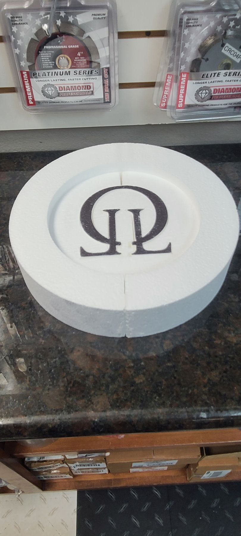 A white plate with a black logo on it is sitting on a counter.