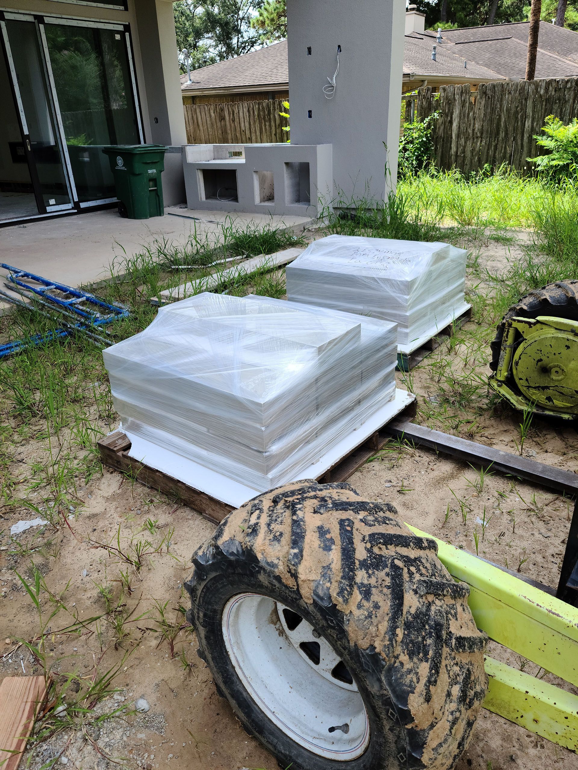 A forklift is carrying a stack of concrete blocks in a yard.