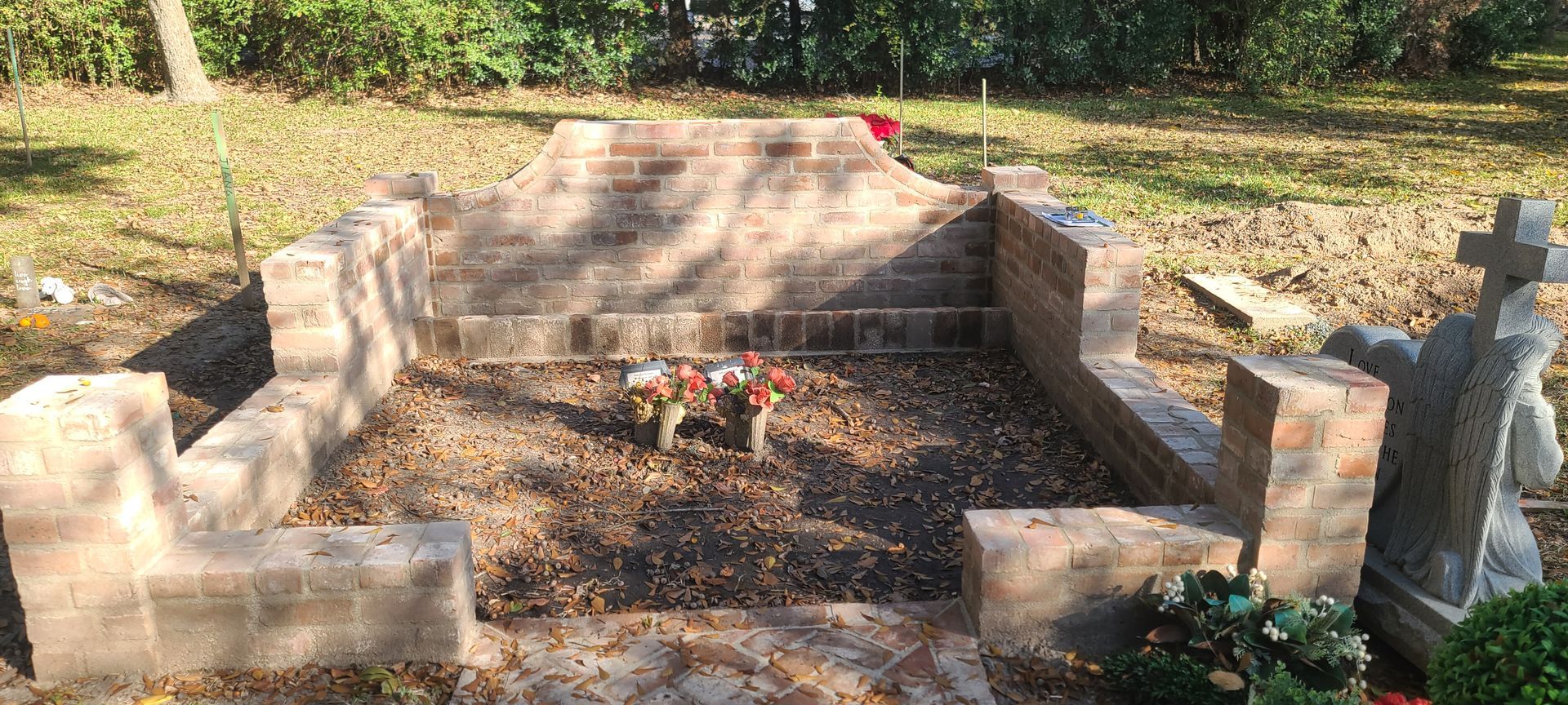 There is a statue of a cross in the middle of a cemetery.