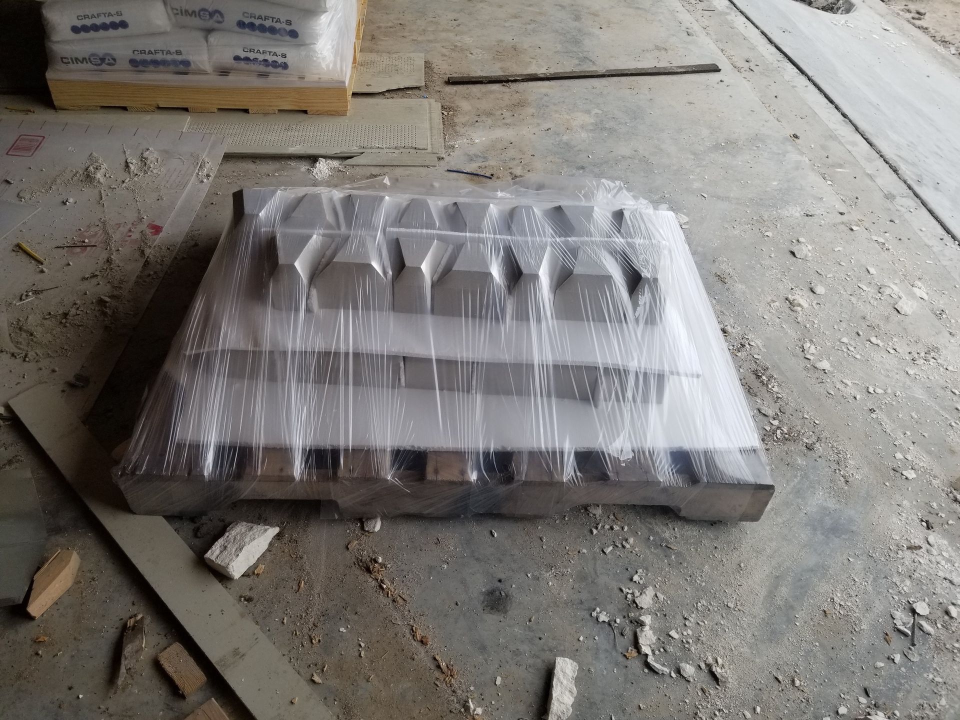 A piece of metal wrapped in plastic sits on a pallet