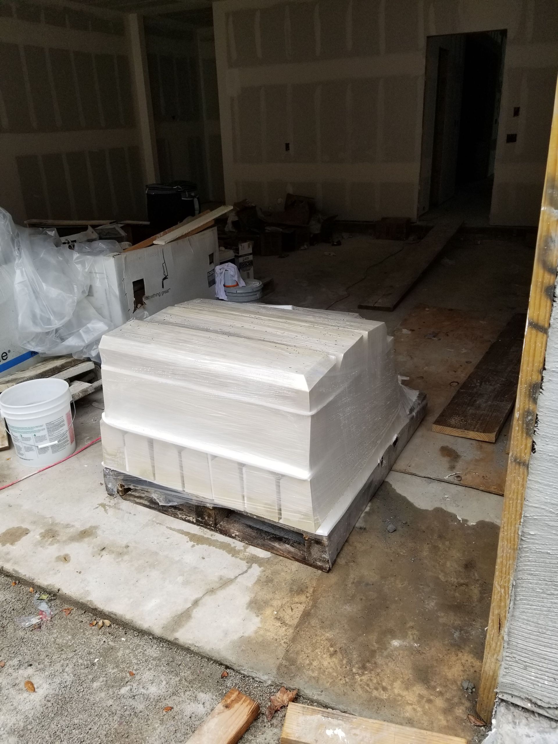 A large white box is sitting on top of a wooden pallet in a room under construction.