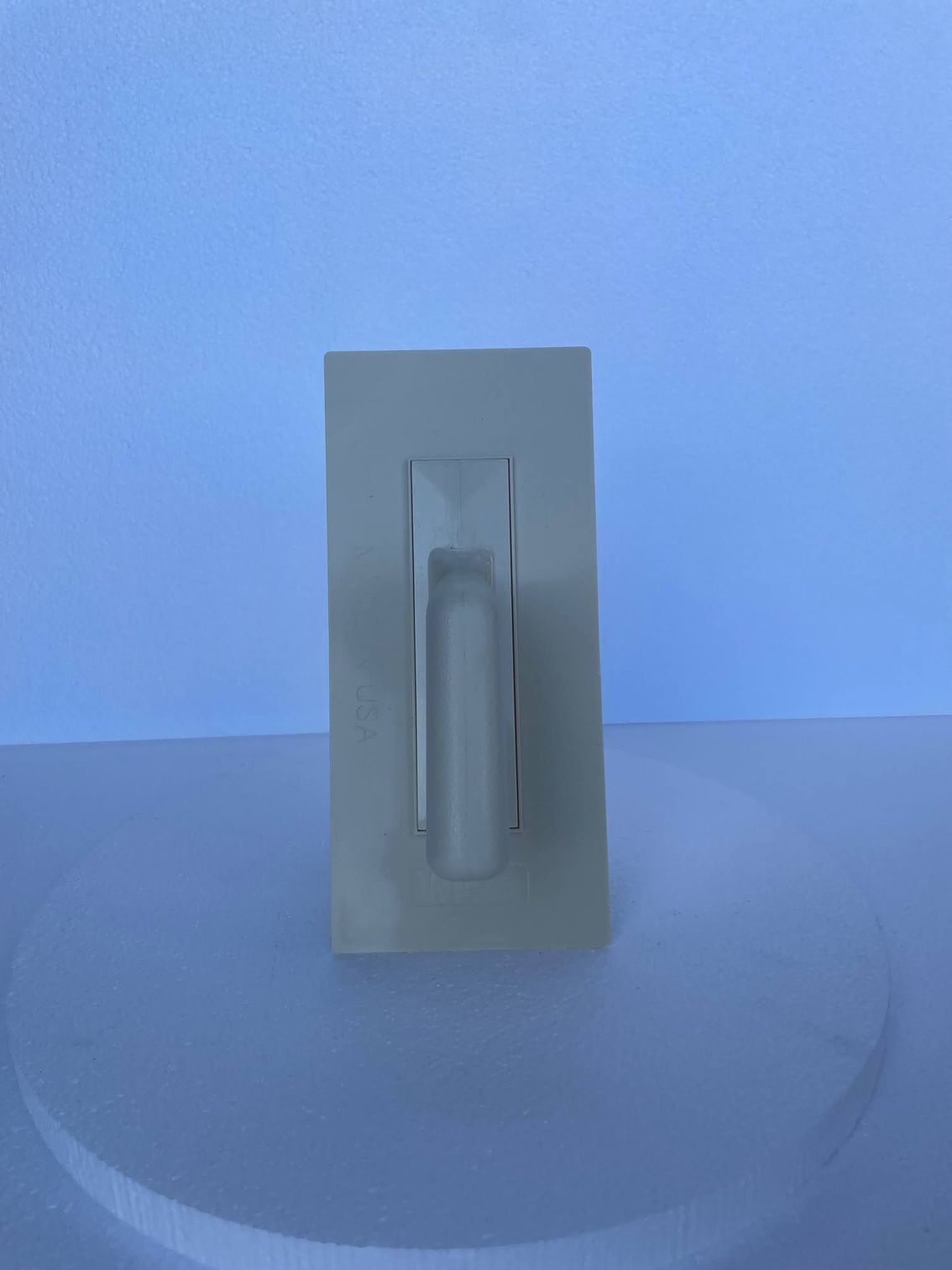 A white light switch is sitting on top of a white table.