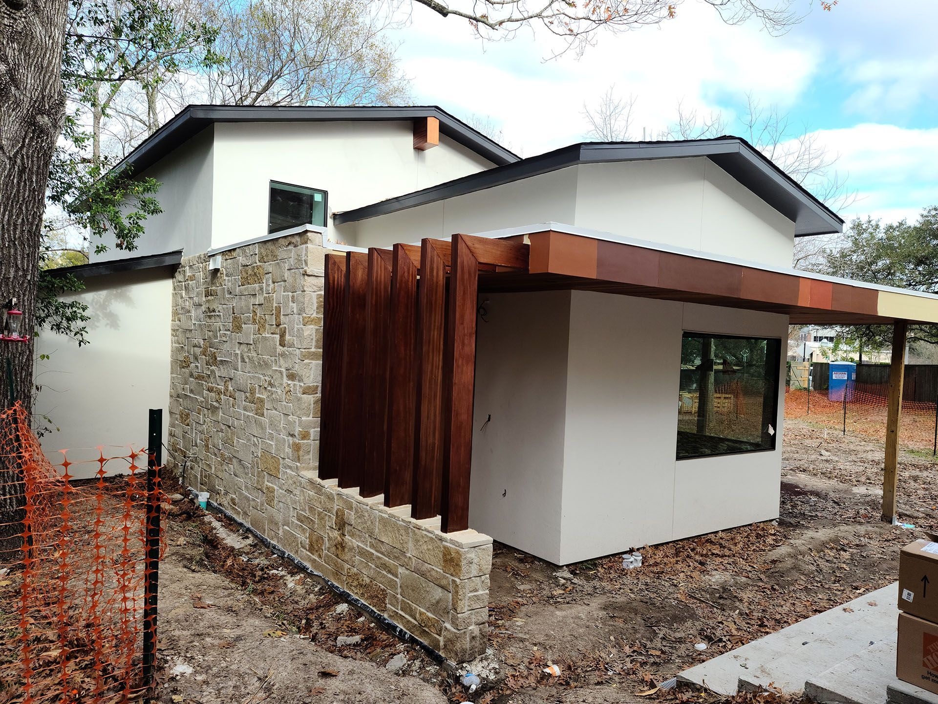 A white house with a stone wall and a wooden roof
