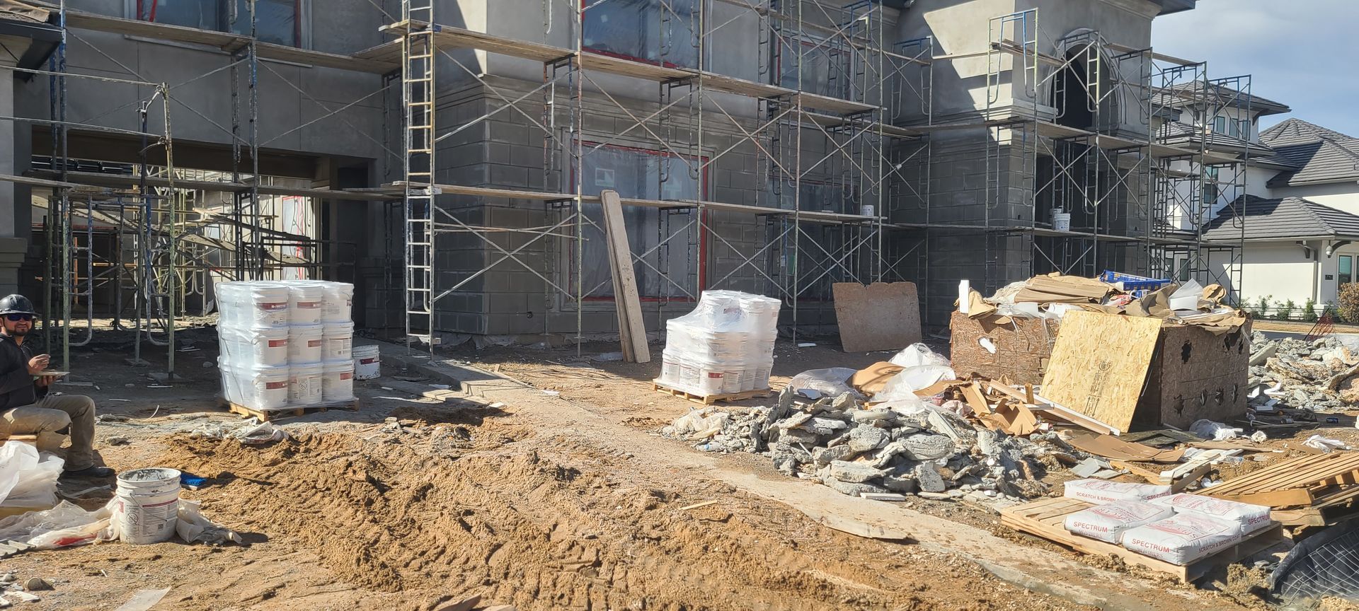 A construction site with scaffolding and a pile of dirt in front of a building under construction.