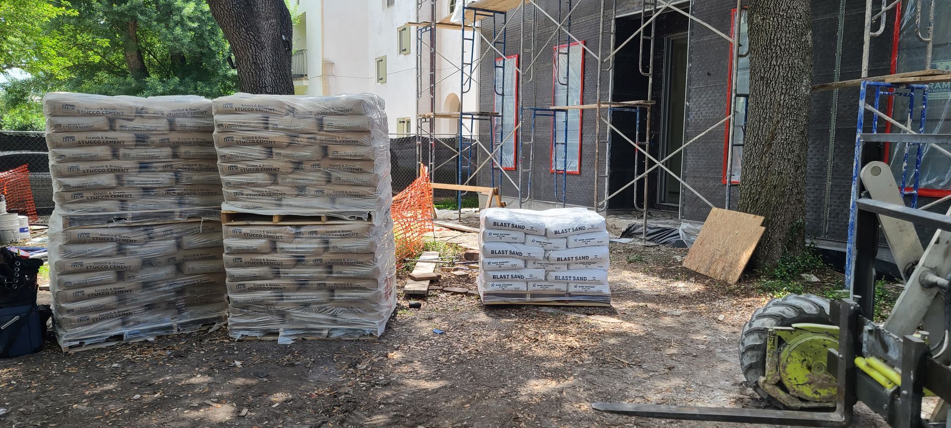 A stack of bricks sitting on top of a pile of dirt in front of a building under construction.