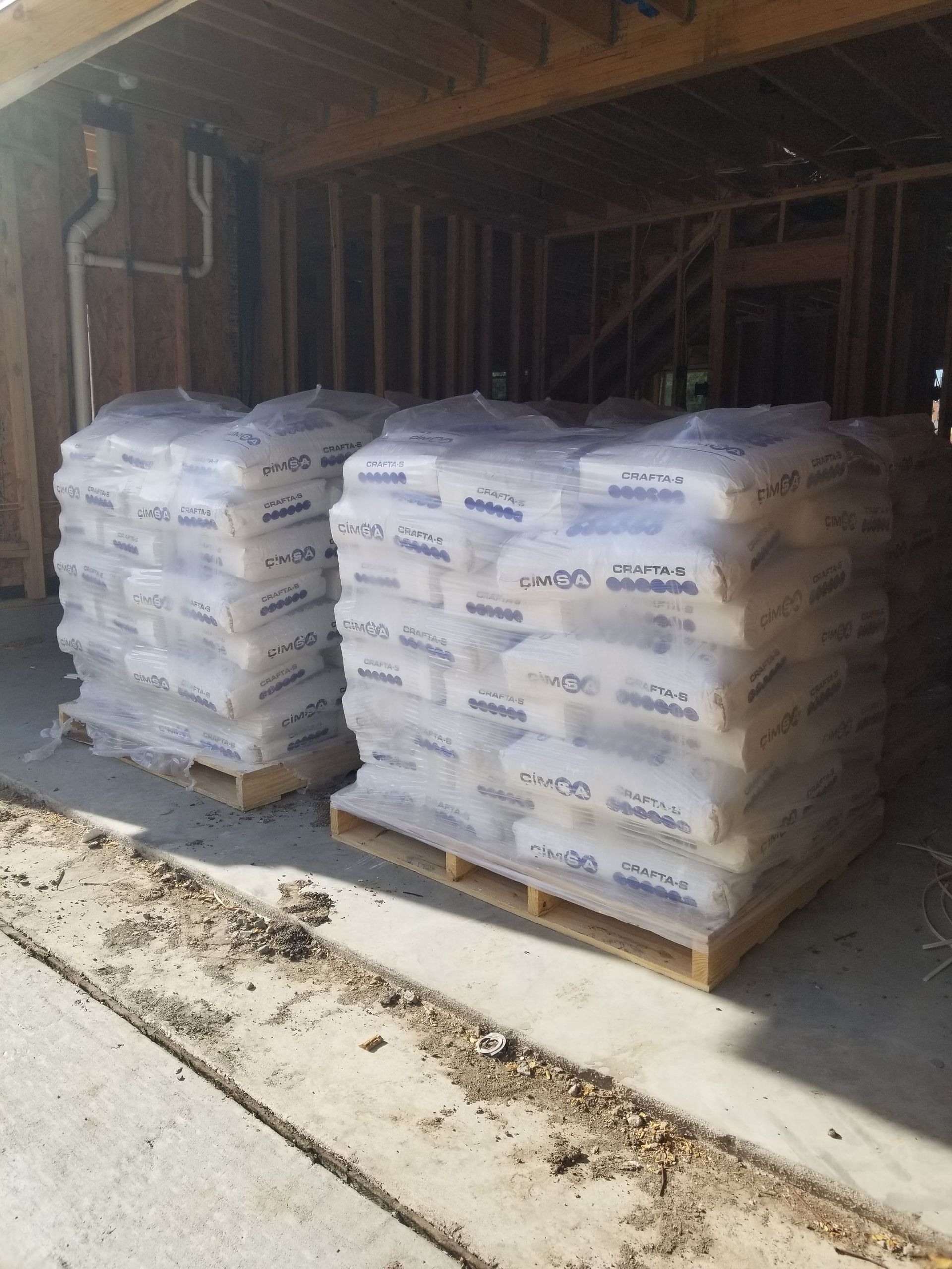 Two wooden pallets filled with bags of sand in front of a building under construction