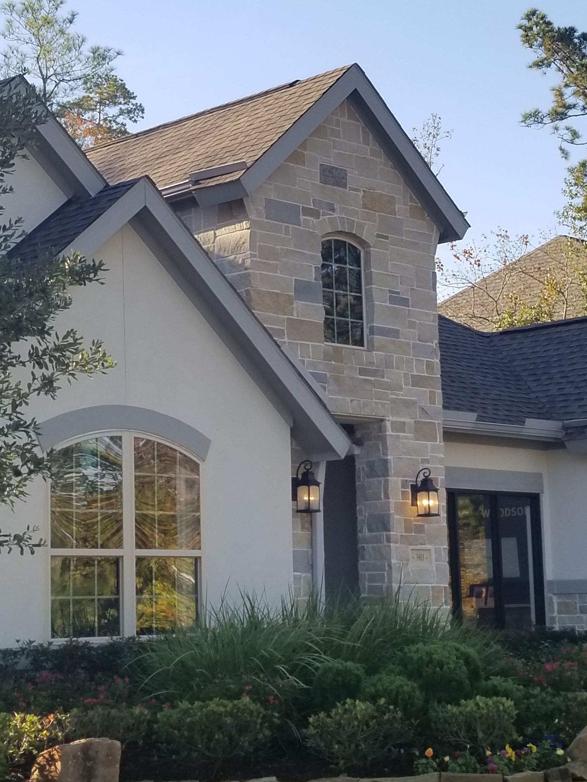 A white house with a stone facade and a gray roof