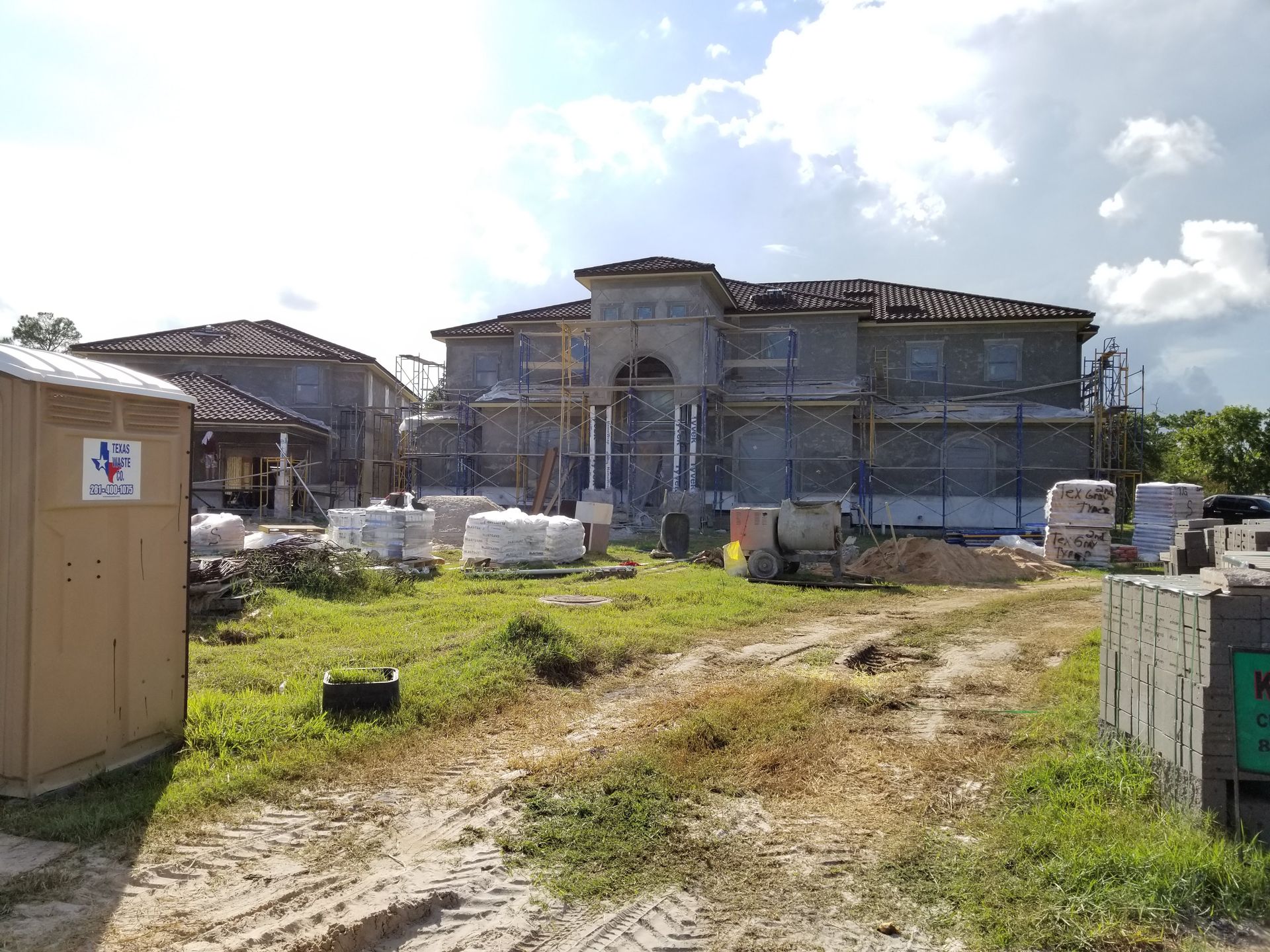 A large house is being built on a dirt road.
