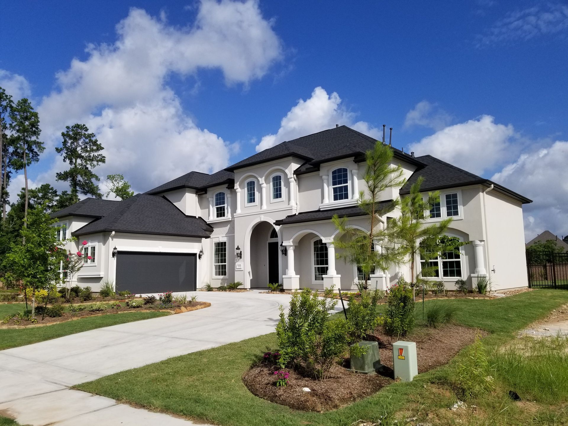 A large white house with a black roof and a driveway