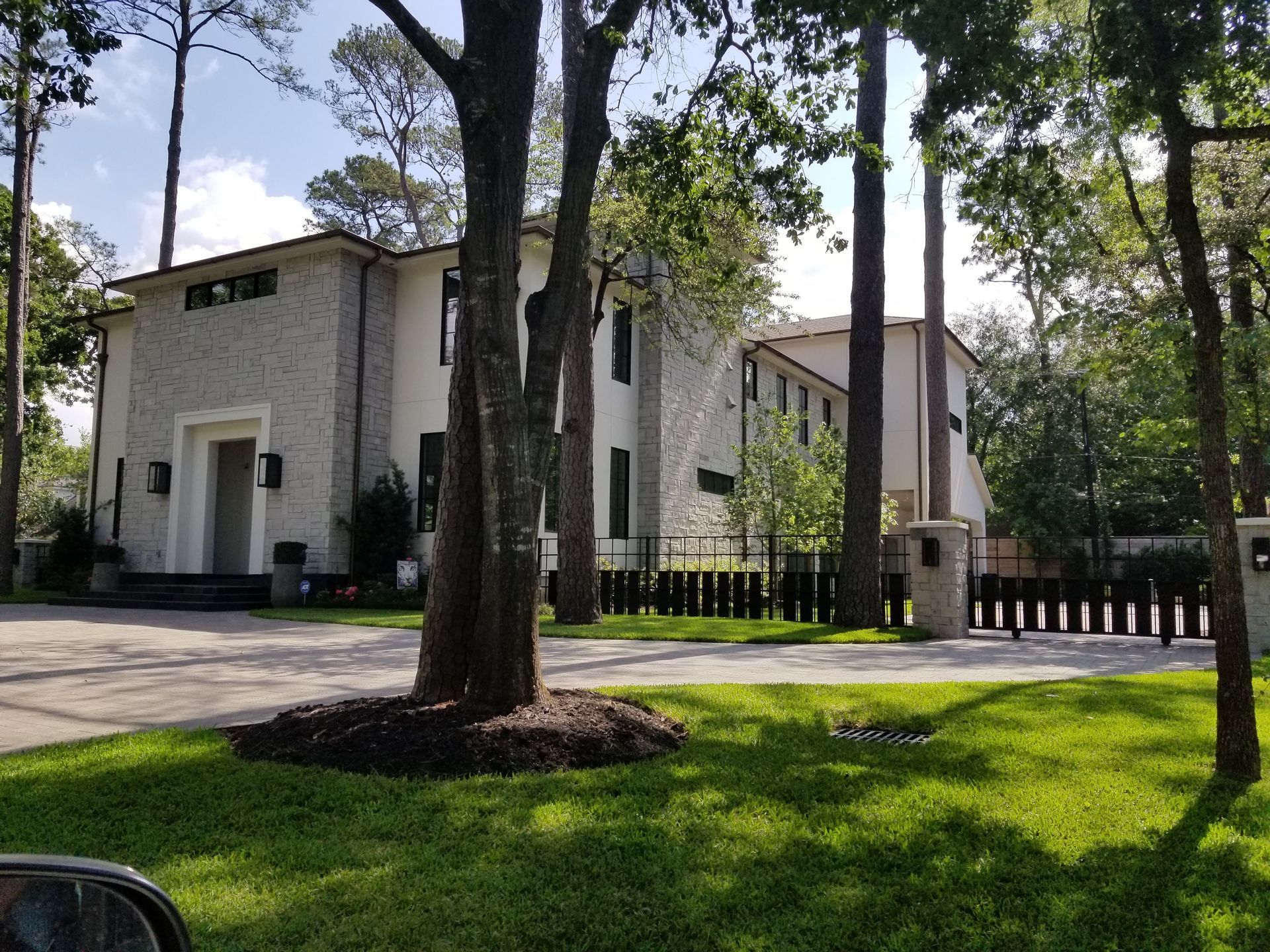 A large white house is surrounded by trees and grass.