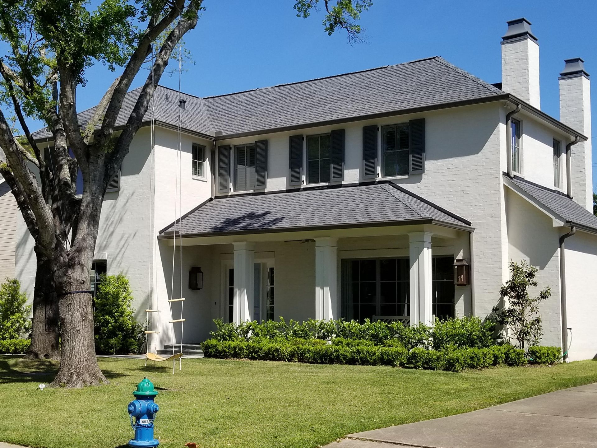 A white house with a blue fire hydrant in front of it