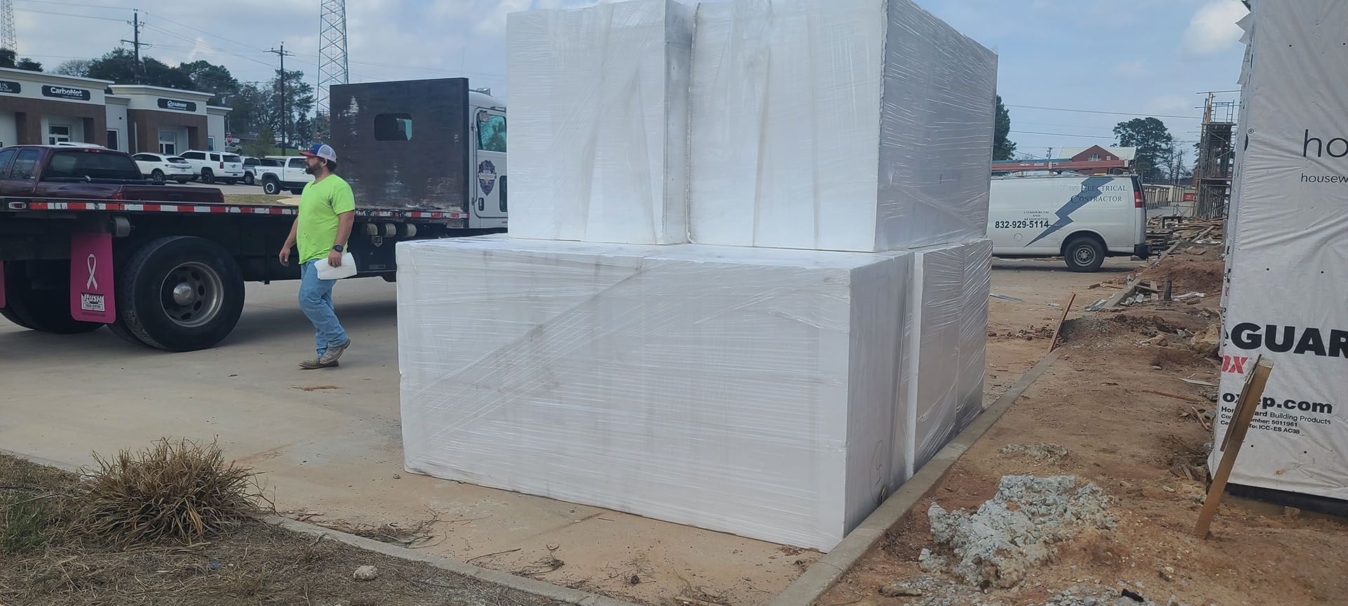 A man is standing next to a stack of styrofoam blocks.