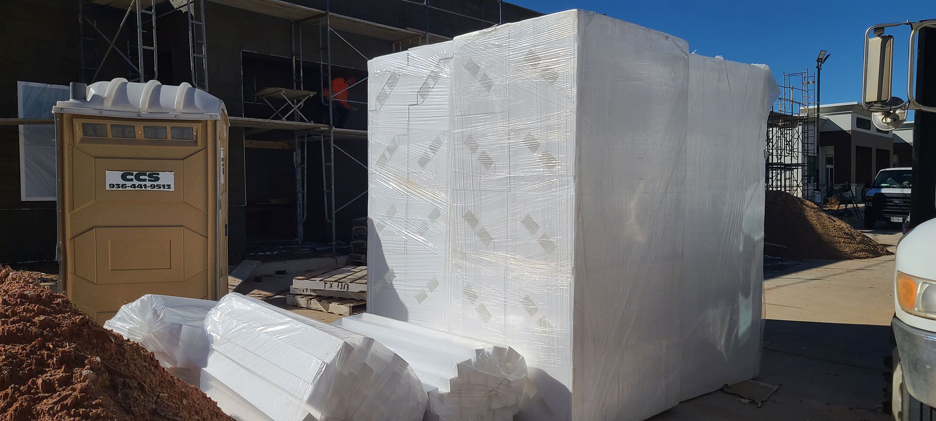 A large white block of styrofoam is sitting in front of a building under construction.