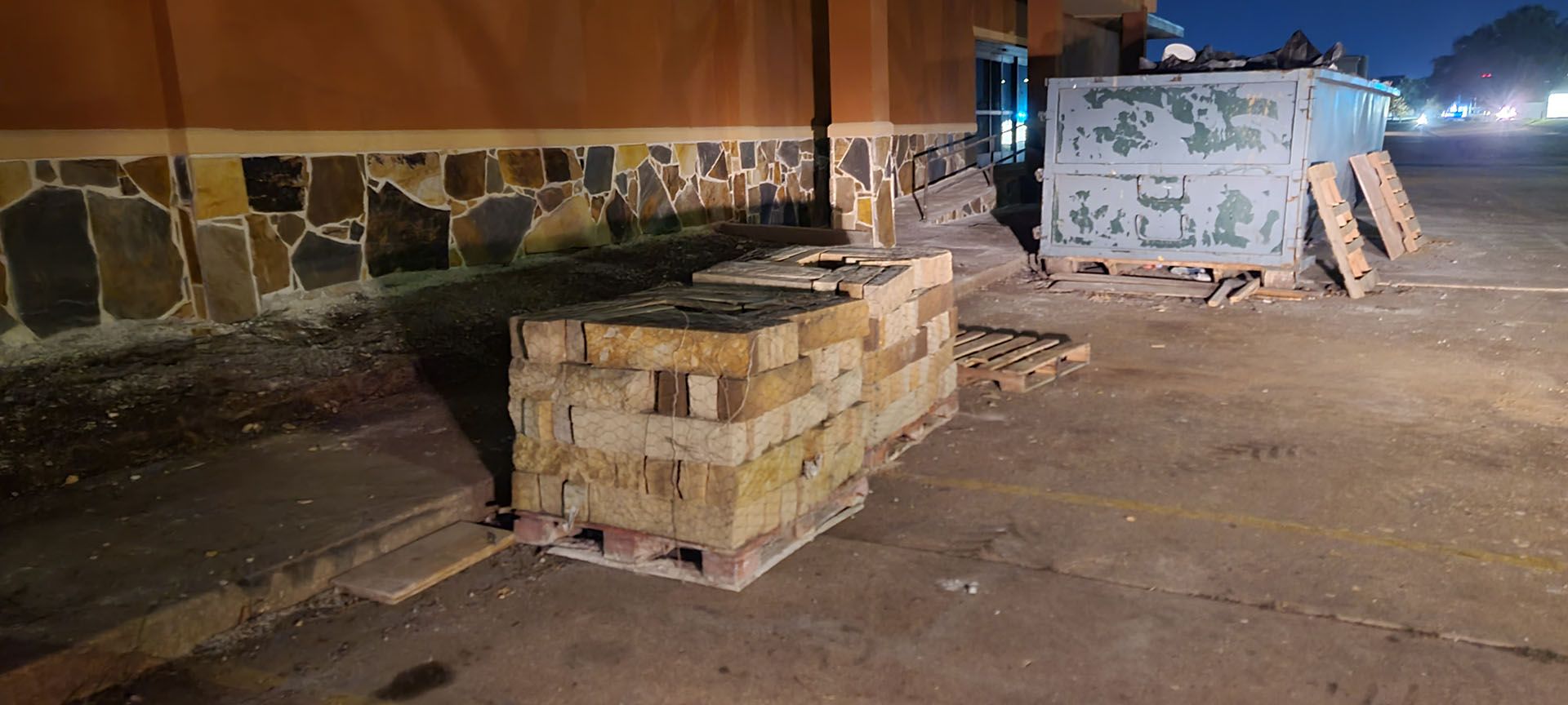 A pile of bricks is sitting on a wooden pallet in front of a building.