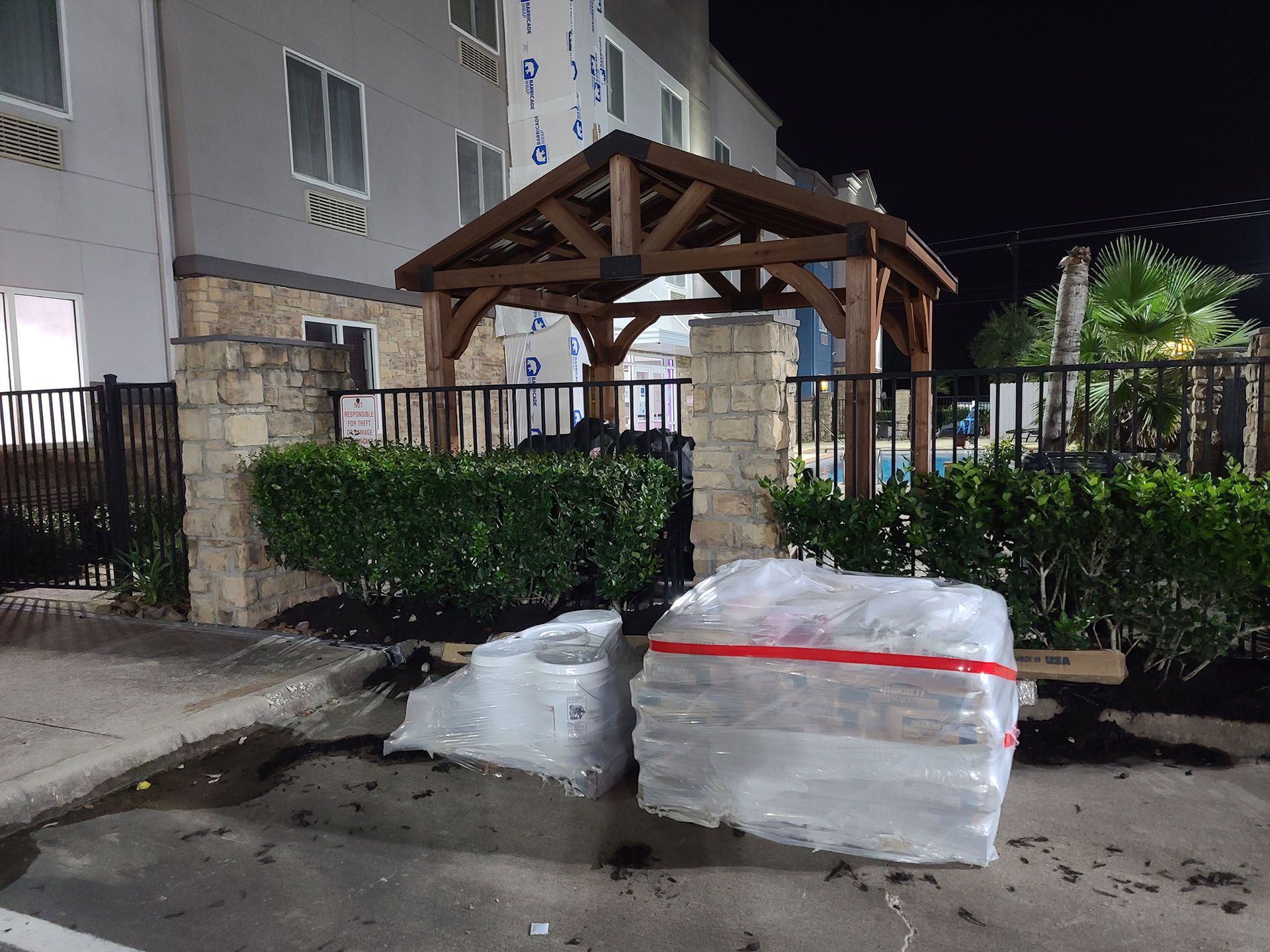 A wooden gazebo is being built in a parking lot at night.