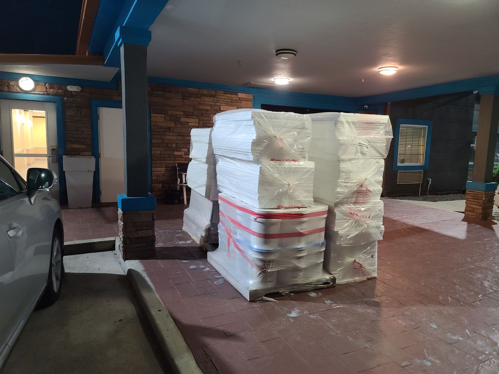 A stack of styrofoam blocks in a parking lot next to a car.