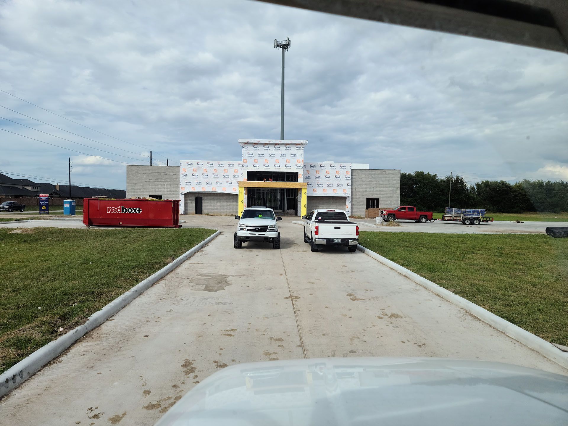 Two white trucks are parked in front of a building under construction