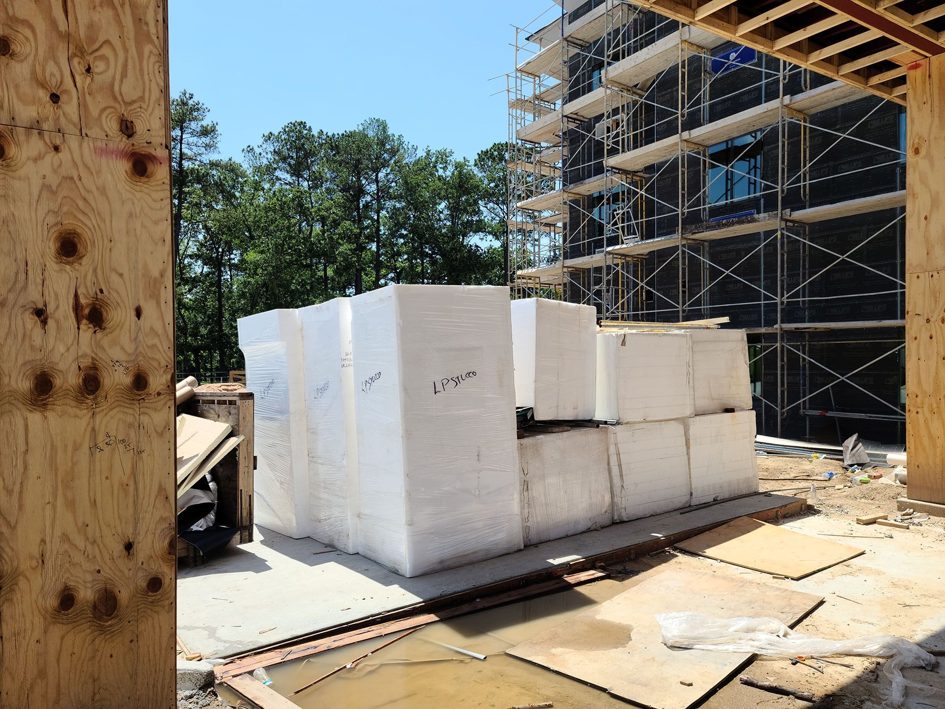 A stack of styrofoam blocks is sitting on the ground in front of a building under construction.