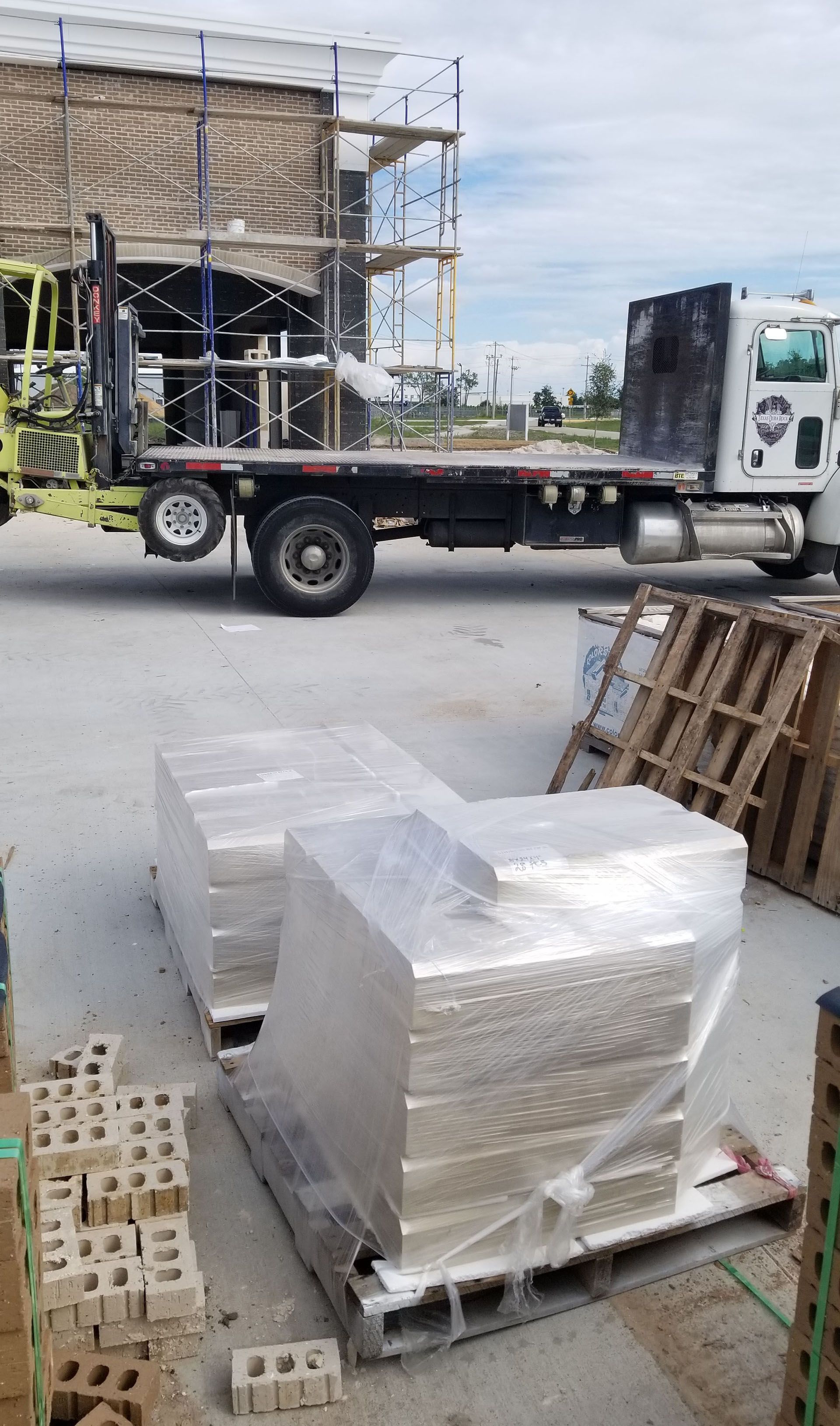 A truck is carrying bricks on a pallet in a parking lot.