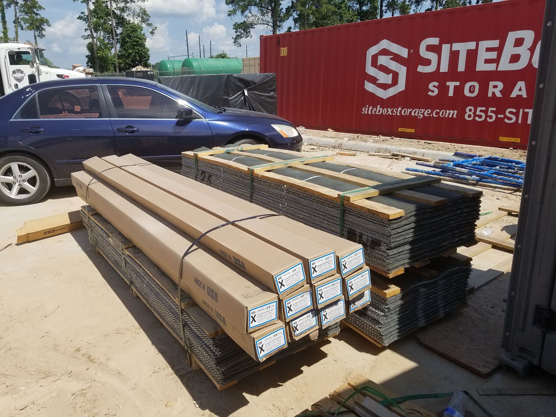 A car is parked in front of a red siteb storage container